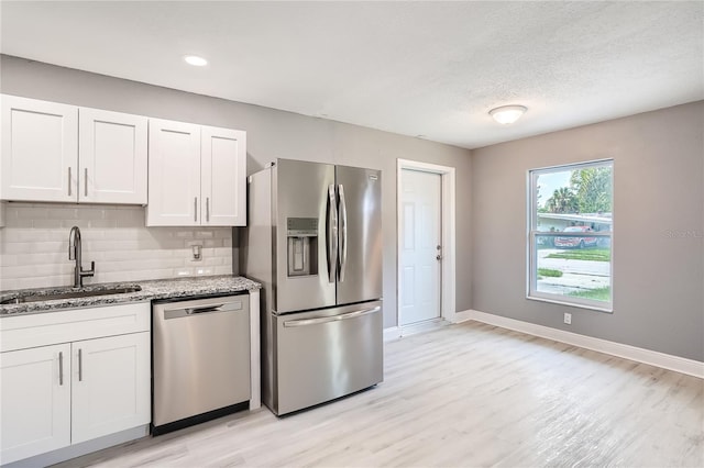 kitchen featuring white cabinets, stainless steel appliances, light stone countertops, and sink