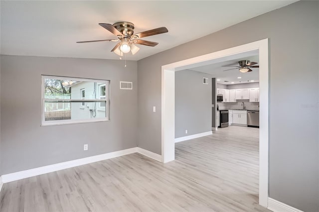 unfurnished room featuring ceiling fan, light hardwood / wood-style flooring, and sink