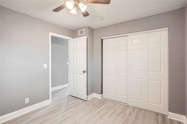 unfurnished bedroom with ceiling fan, light wood-type flooring, and a closet