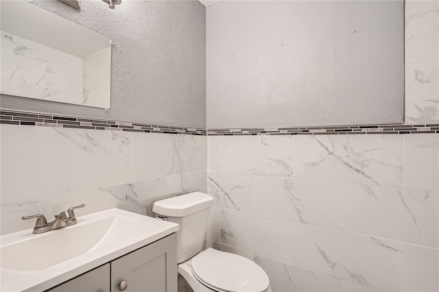 bathroom featuring vanity, toilet, and tile walls