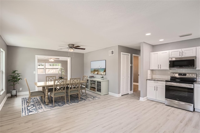 kitchen featuring backsplash, stainless steel appliances, ceiling fan, light hardwood / wood-style flooring, and white cabinets