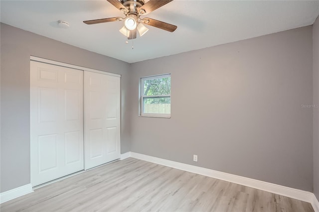 unfurnished bedroom with ceiling fan, light wood-type flooring, and a closet