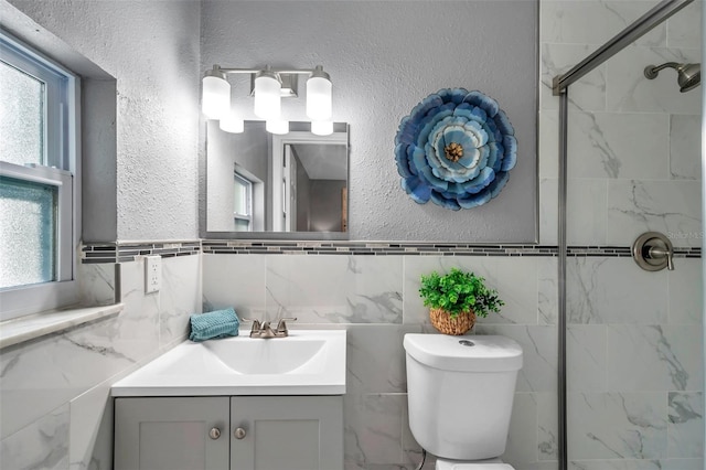 bathroom with vanity, toilet, tile walls, and a healthy amount of sunlight