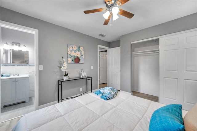 bedroom with connected bathroom, ceiling fan, sink, light hardwood / wood-style flooring, and a closet