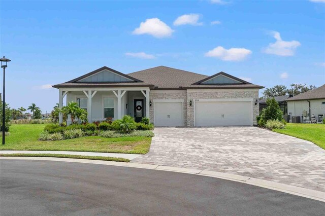 view of front facade with a garage, a front yard, and central AC