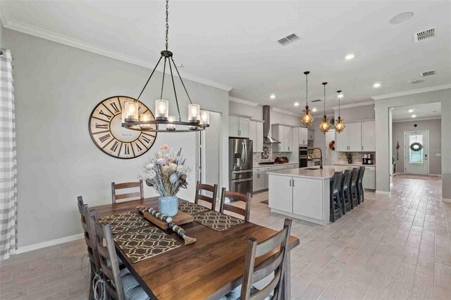 dining area featuring an inviting chandelier, light hardwood / wood-style flooring, crown molding, and sink