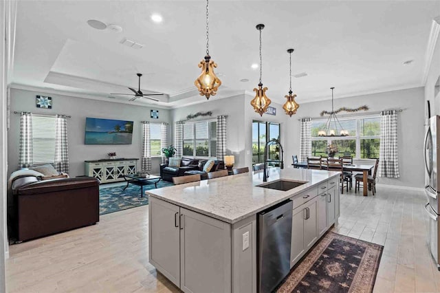 kitchen with sink, pendant lighting, stainless steel appliances, light stone countertops, and a kitchen island with sink