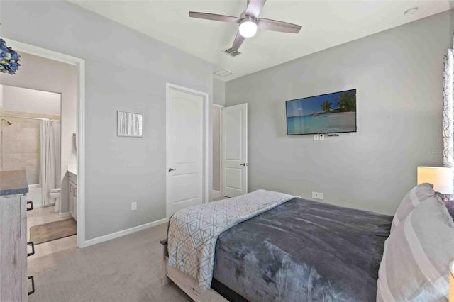 bedroom with ceiling fan, light colored carpet, and ensuite bathroom