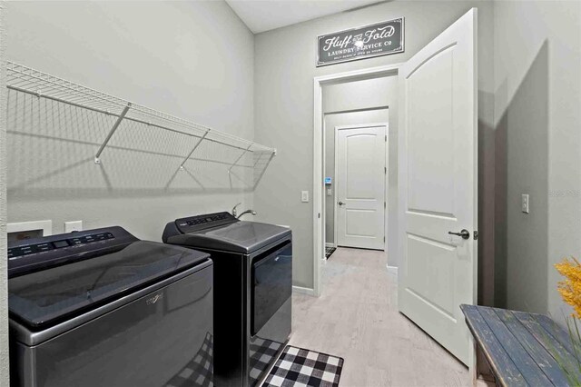 laundry area with washing machine and clothes dryer and light hardwood / wood-style flooring