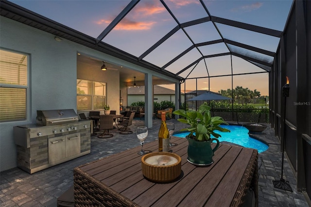 patio terrace at dusk with a lanai and exterior kitchen