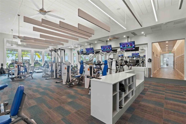 exercise room with ceiling fan and dark carpet