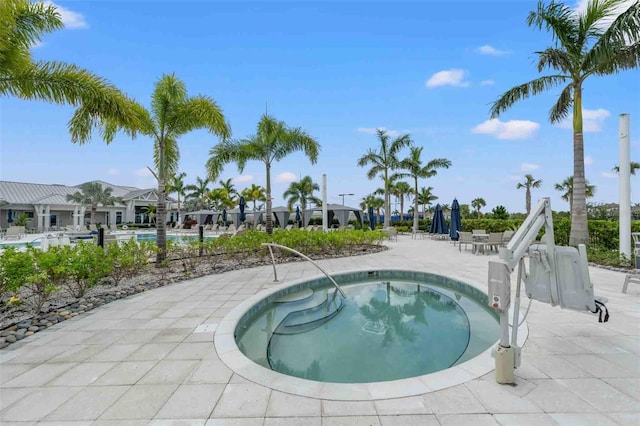 view of swimming pool featuring a hot tub and a patio