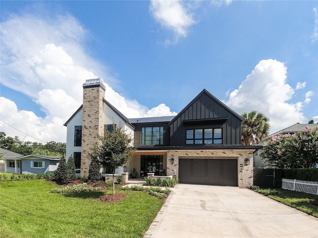 modern farmhouse with brick siding, concrete driveway, board and batten siding, a front yard, and fence