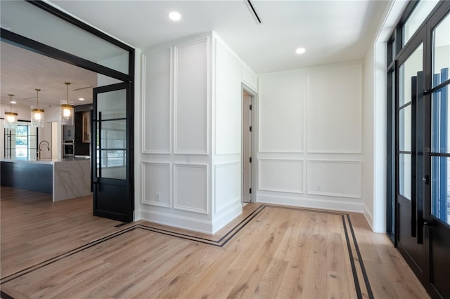 interior space with light wood finished floors, recessed lighting, a sink, and a decorative wall