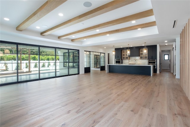 unfurnished living room with light wood-style floors, recessed lighting, a healthy amount of sunlight, and beamed ceiling