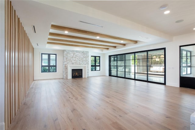 unfurnished living room with beam ceiling, a fireplace, light wood-style flooring, and baseboards