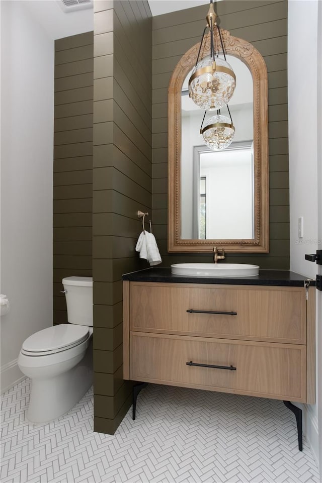 bathroom featuring tile patterned flooring, toilet, wooden walls, visible vents, and vanity