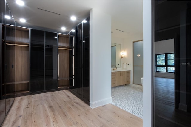 hallway featuring light wood finished floors, a sink, and baseboards