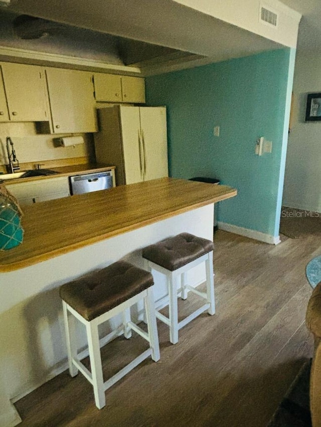 kitchen featuring hardwood / wood-style floors, sink, white fridge, dishwasher, and cream cabinetry