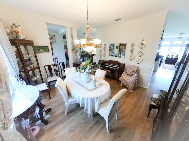 dining space featuring ceiling fan with notable chandelier and light hardwood / wood-style flooring