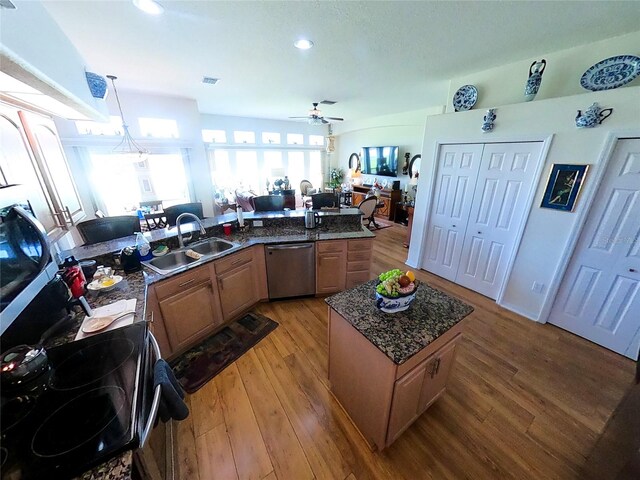 kitchen featuring light hardwood / wood-style floors, a kitchen island with sink, sink, hanging light fixtures, and stainless steel dishwasher