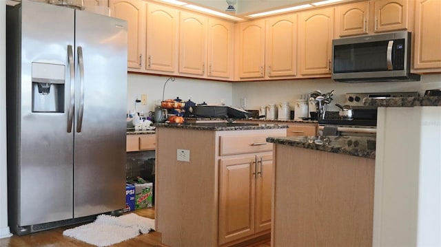 kitchen with dark stone countertops, light brown cabinets, appliances with stainless steel finishes, and dark hardwood / wood-style flooring