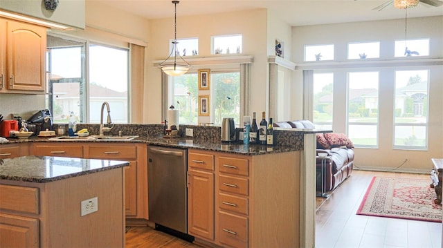 kitchen with a wealth of natural light, hanging light fixtures, sink, and stainless steel dishwasher