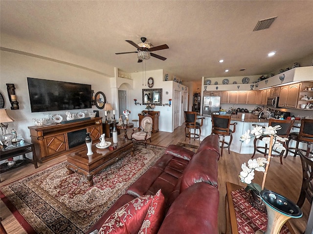 living room featuring ceiling fan, hardwood / wood-style flooring, and a textured ceiling