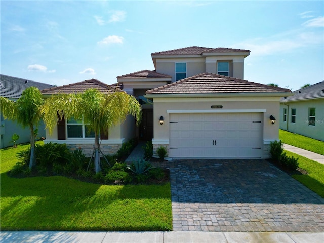 mediterranean / spanish house with a garage, a front yard, decorative driveway, and stone siding