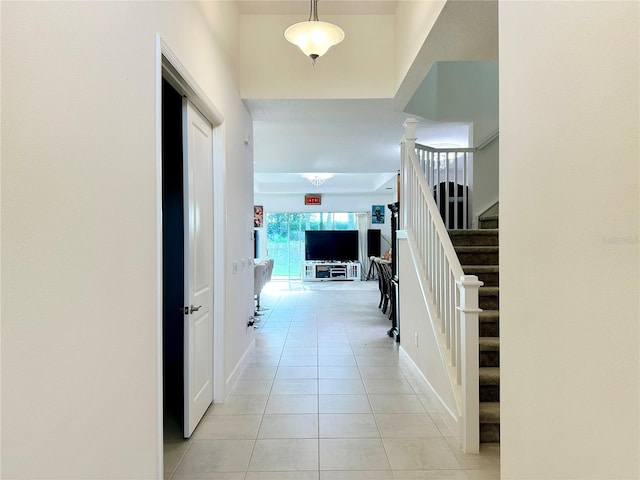 hall featuring stairway, light tile patterned flooring, decorative columns, and baseboards