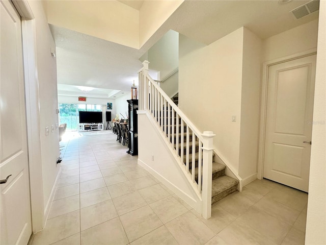 stairway featuring tile patterned flooring, visible vents, and baseboards