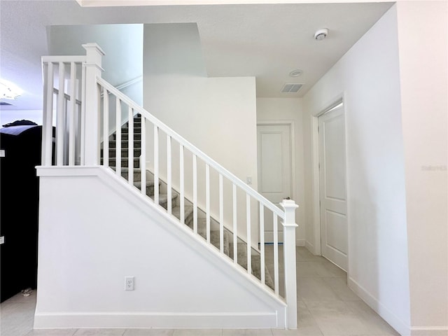 stairway featuring visible vents, baseboards, and tile patterned floors