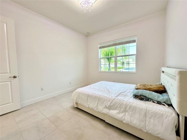 bedroom with a textured ceiling, baseboards, and light tile patterned floors