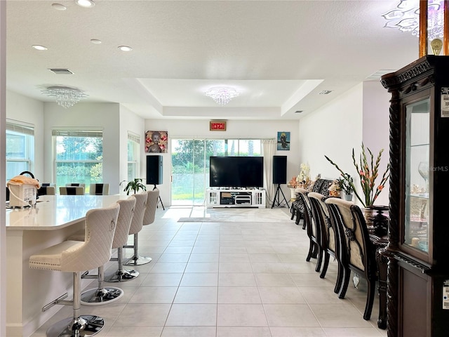 dining space featuring a tray ceiling, light tile patterned floors, recessed lighting, visible vents, and a textured ceiling