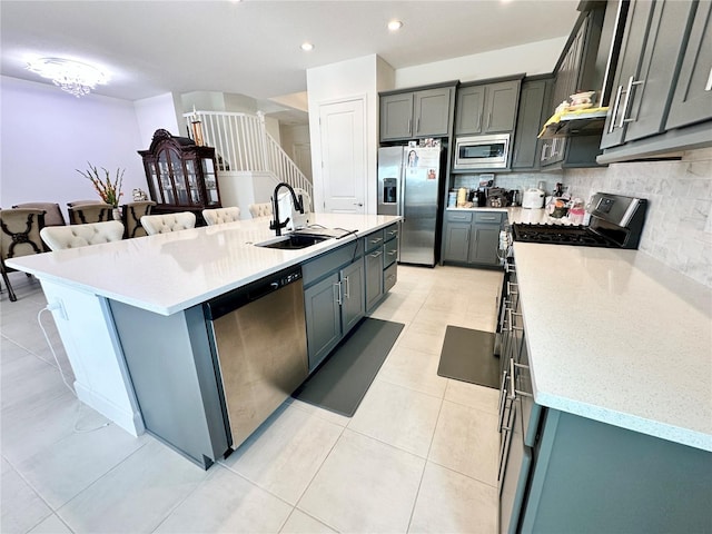 kitchen with light tile patterned floors, appliances with stainless steel finishes, a sink, and decorative backsplash