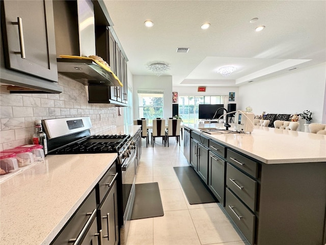 kitchen with light tile patterned flooring, visible vents, open floor plan, wall chimney range hood, and appliances with stainless steel finishes