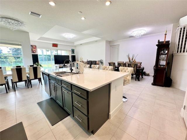 kitchen with visible vents, open floor plan, light countertops, dishwasher, and a raised ceiling