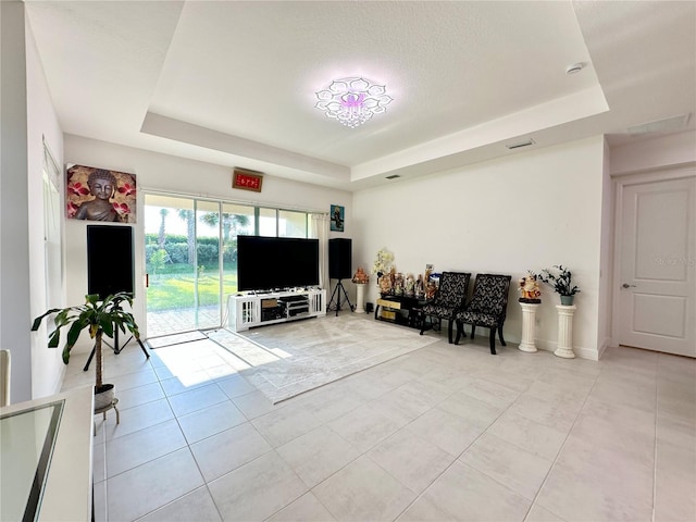 living room featuring a tray ceiling, light tile patterned flooring, and visible vents