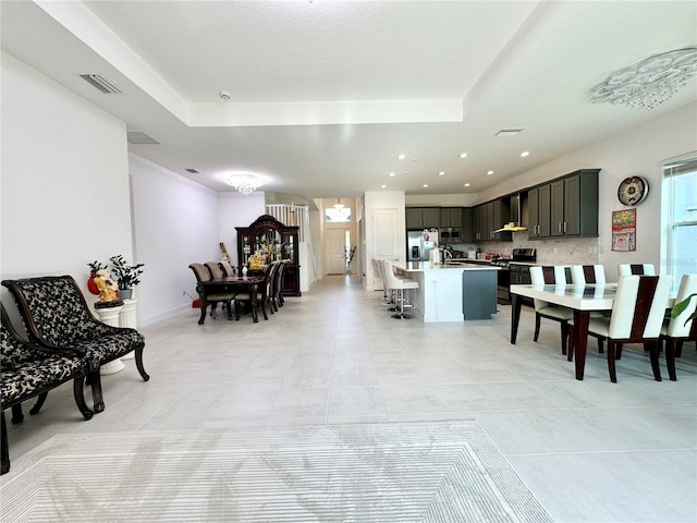 dining room featuring recessed lighting, a raised ceiling, and visible vents