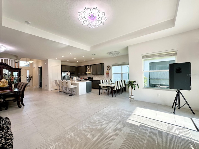 living room featuring a tray ceiling, recessed lighting, and light tile patterned floors