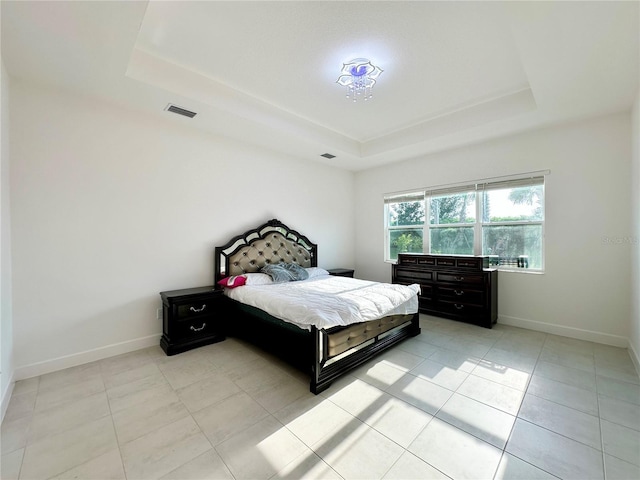 bedroom featuring a tray ceiling, visible vents, baseboards, and light tile patterned floors