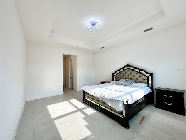 bedroom with visible vents, a tray ceiling, and baseboards