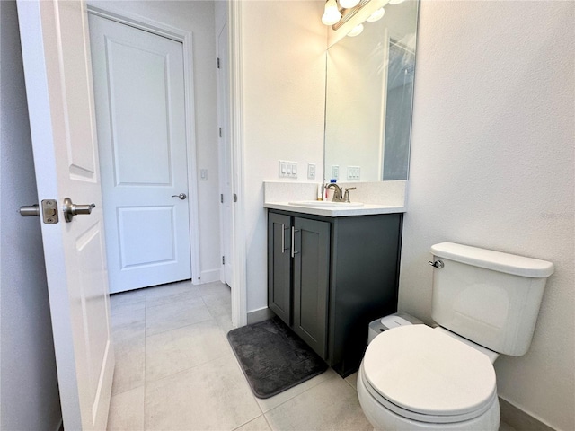 bathroom with toilet, baseboards, vanity, and tile patterned floors