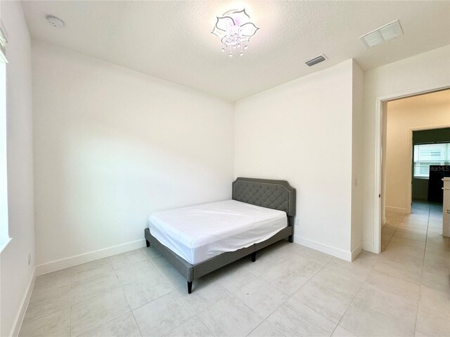 bedroom featuring a textured ceiling, visible vents, and baseboards