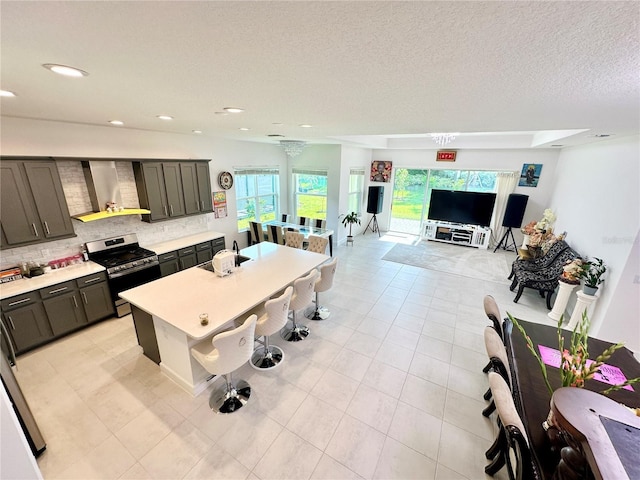 kitchen featuring tasteful backsplash, recessed lighting, light countertops, gas range, and wall chimney exhaust hood