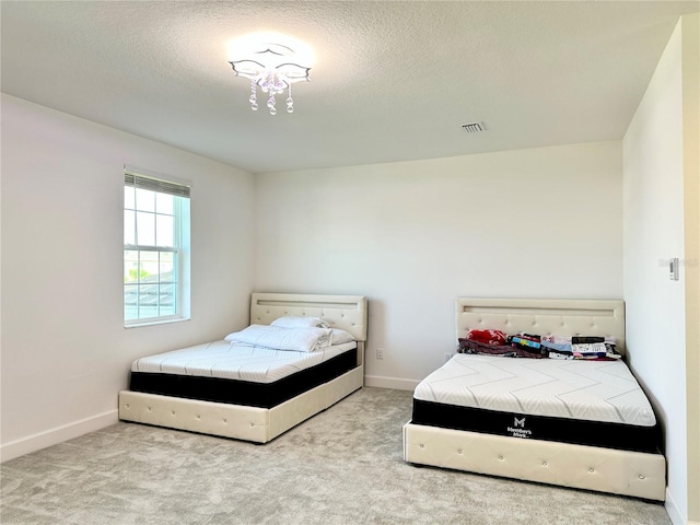 bedroom with carpet, visible vents, a textured ceiling, and baseboards