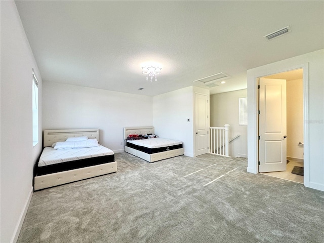 unfurnished bedroom featuring baseboards, carpet, visible vents, and attic access