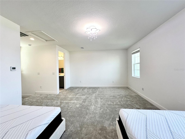 carpeted bedroom featuring a textured ceiling, visible vents, attic access, and baseboards