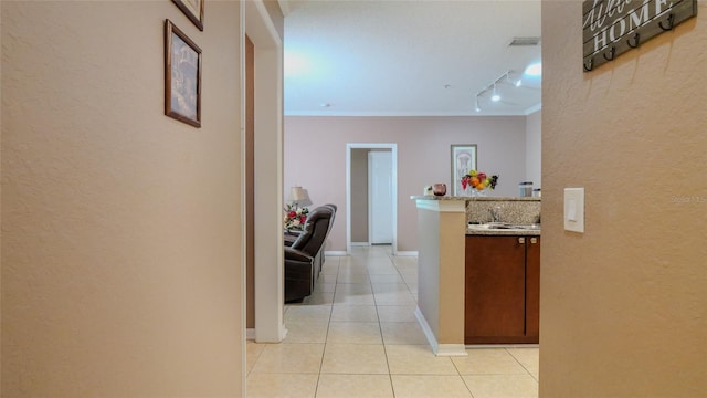 hall featuring light tile patterned flooring, rail lighting, and ornamental molding