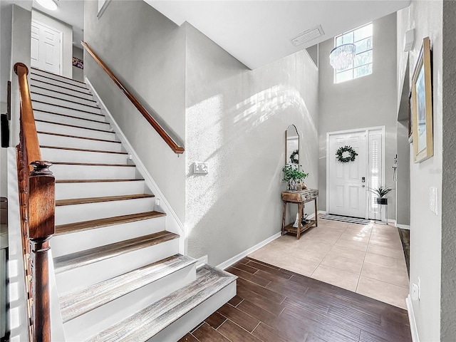 entrance foyer with a towering ceiling and wood-type flooring